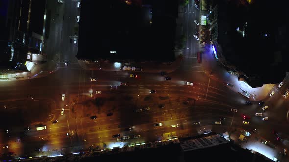 A beautiful sports car drives at night along modern city streets among skyscrapers and houses.  alt