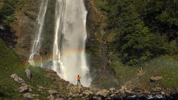 Hiker Near Waterfall with Rainbow