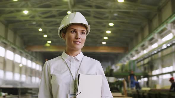 Successful businesswoman staying in helmet at factory