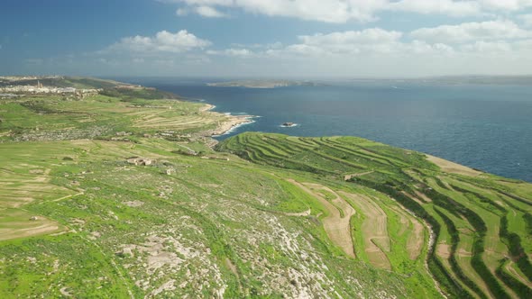 AERIAL: Greenery Plains of Ta Cenc Cliffs near Blue Mediterranean Sea in Gozo Island