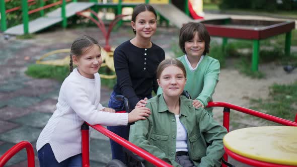 Motivated Caucasian Girl Posing on Playground with Friends Looking at Camera Smiling alt
