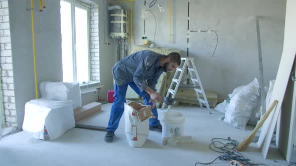 Male Contractor Preparing Stucco in Bucket During Renovation