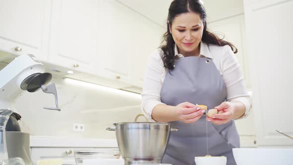 A Woman Breaks an Egg and Separates Yolks From Proteins alt