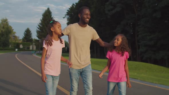 Joyful Father and Two Daughters Relaxing in Park alt