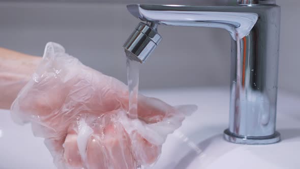 Close-up View of a Woman's Hand Washing the Faucet in the Bathroom Using a Detergent and alt