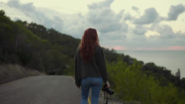 Female photographer walking on a road in the evening alt