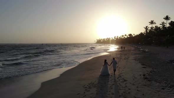 Drone Footage of the Beautiful Sunset at the Tropical Beach with Couple Walking alt