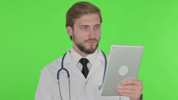 Video Call on Tablet By Young Doctor on Green Background alt