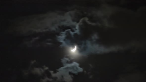 Time lapse: the moon lighting through clouds in dark night sky. 4K
