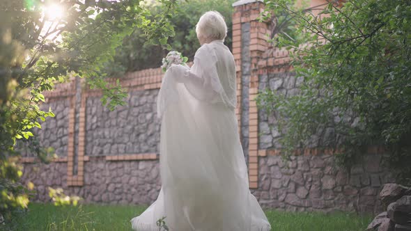 Cheerful Beautiful Senior Bride Spinning Dancing in Slow Motion Outdoors in Sunshine alt