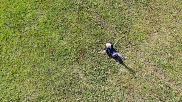 man laying on green grass relaxing aerial shot