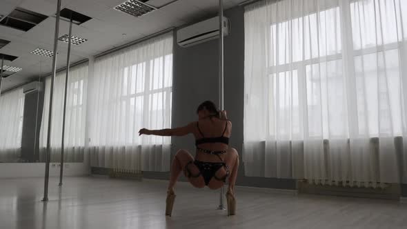 Flexible Woman Dancing on Pole in Studio