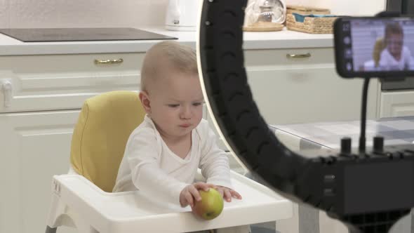 Parents Record Video on Smartphone of Kid in High Chair at Home Recording with Mobile Phone and Ring alt