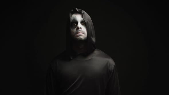 Young Man Dressed Up Like Grim Reaper Over Black Background alt