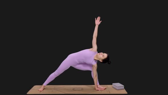 Young Woman Doing Extended Side Angle Pose while Practicing Yoga, Alpha in