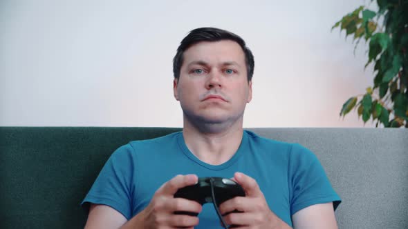 A man in front of the TV is holding a joystick in his hands, playing the console