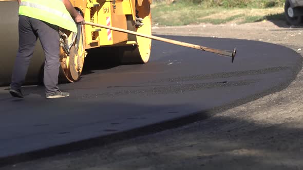 Road Repair. Asphalt Laying. Worker Levels the Newly Laid Road Surface and the Roller Makes the alt