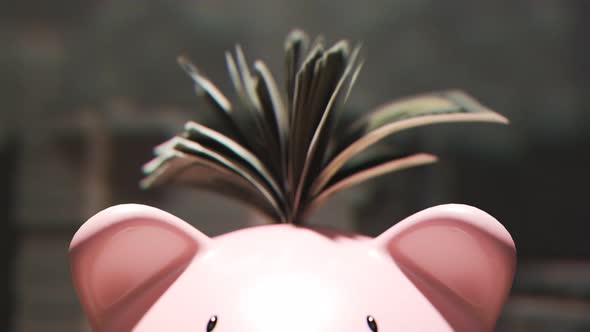 Cute pink piggy bank stuffed with dollars and surrounded by piles of money. 4KHD alt