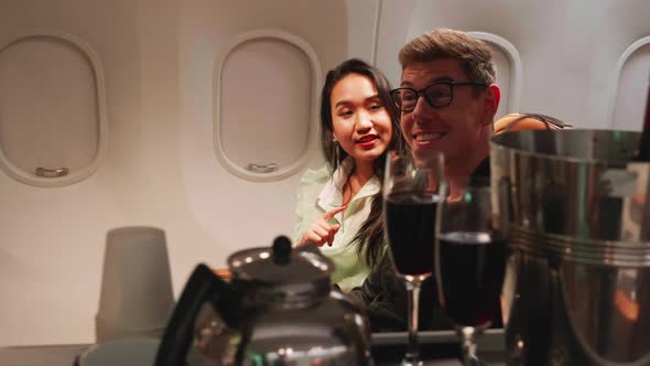 happy couple order champagne from stewardess on airplane, airline service concept