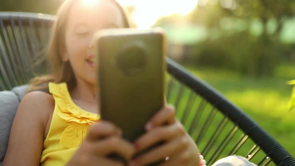 Happy kid girl holding smartphone having video call with friend distantly