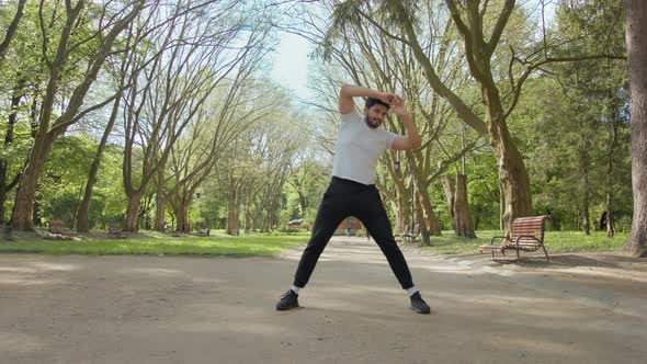 Healthy Muslim Guy in Sport Outfit Doing Flexible Exercises Outdoors alt