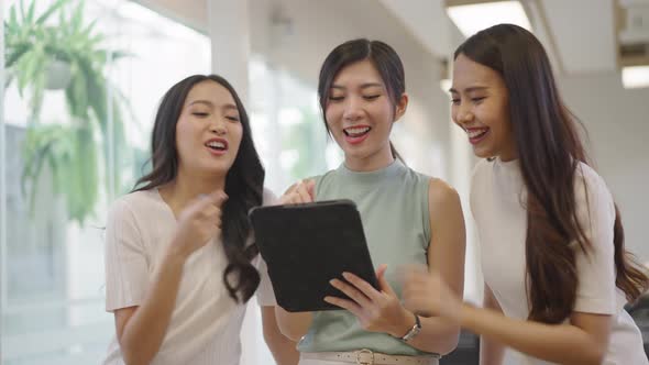 Asian female colleagues looking at tablets together at the office