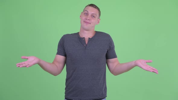 Portrait of Confused Young Man Shrugging Shoulders alt