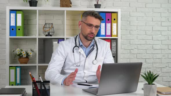 Doctor wears white medical coat consults patient online video call laptop webcam alt