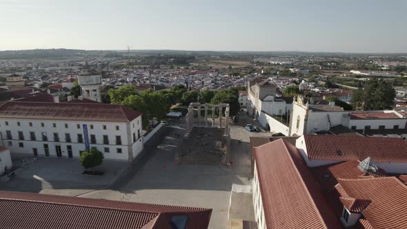 Ruins of Roman Temple in Evora historic center with cityscape in background, Portugal. Aerial orbit