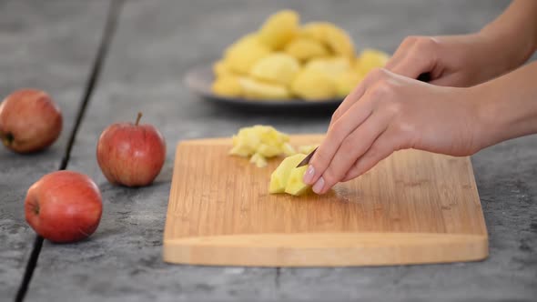 Woman is standing in her kitchen, cutting apples.