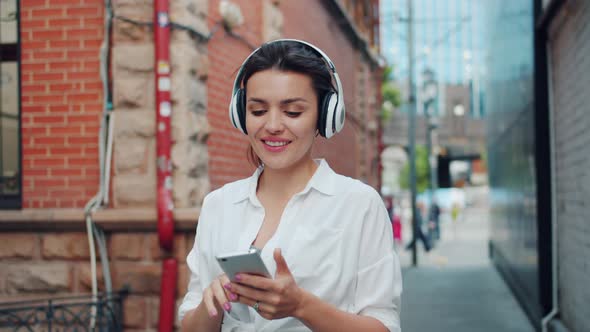Portrait of Lady Enjoying Music in Headphone Using Smartphone Outdoors Walking alt