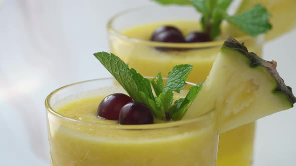 Pineapple smoothies drinks in the glasses being garnished with berries