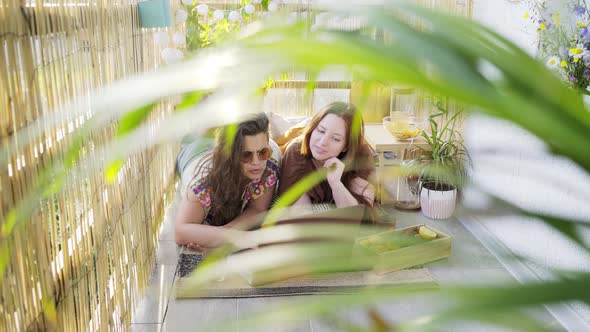 Girlfriends Use Laptop and Relax on Balcony