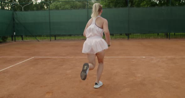 Back View of Fit Sportswoman Receiving Ball on Clay Court Background Slow Motion Handheld Device