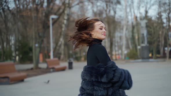 Fashionable girl with long hair looking at camera outdoors. alt