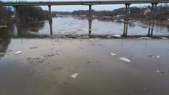 Road Bridge Over a Dim River Stream with Floating Ice Floes alt