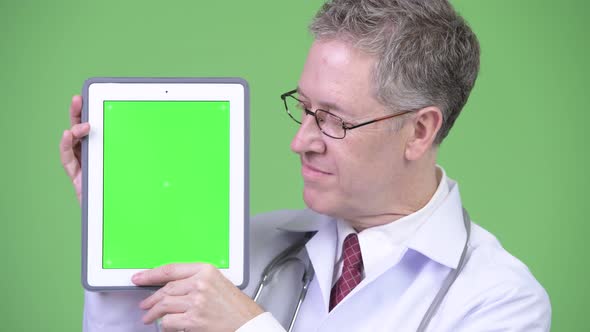Portrait of Happy Mature Man Doctor Showing Digital Tablet