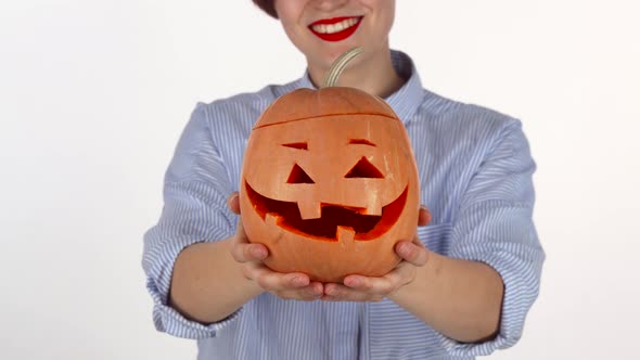 Red Lipped Woman Holding Out Carved Halloween Pumpkin To the Camera alt