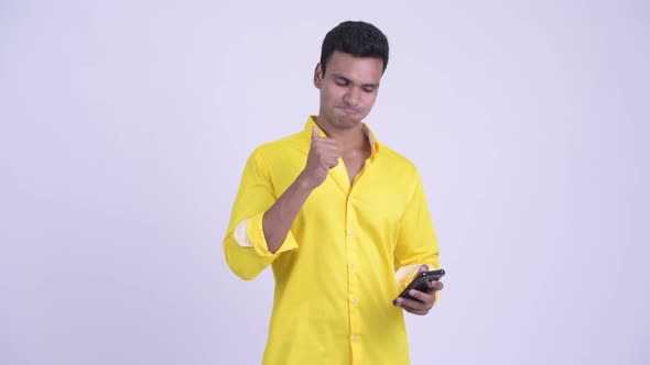 Happy Young Indian Businessman Using Phone and Looking Surprised alt