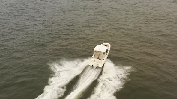 An aerial view of a small, white fishing boat speeding in the deep, green Atlantic Ocean by Long Isl alt