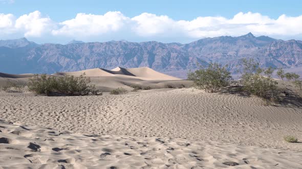 Sand dunes of the Mojave Desert with people exploring the area, Aerial rising shot alt