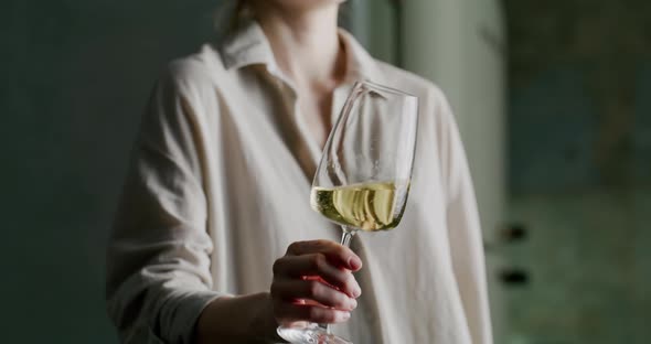 Glass of White Wine Shimmers Beautifully in the Light in a Woman's Hand