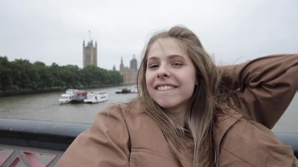 Woman takes a selfie during a windy day in London alt