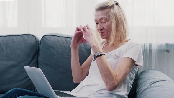 Old Woman Making Heart Shape in Front of the Laptop While Chatting with Her Family alt