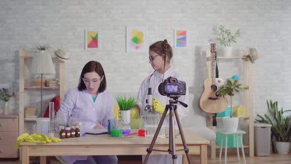 Woman and Teenage Girl Bloggerconducting an Experiment Looking Through a Microscope in a Chemical alt