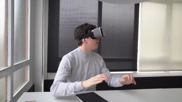 Youn businessman sitting in office using virtual reality simulator alt