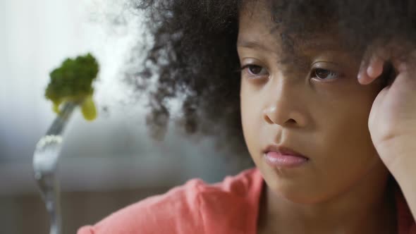 Cute African American Kid Looking at Fork With Broccoli Piece, Organic Food alt