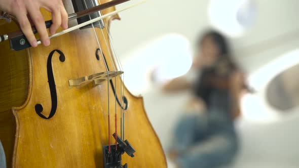 Closeup of a Playing the Cello in the Background Playing the Violin alt