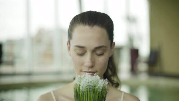 Young woman smelling fresh flowers alt