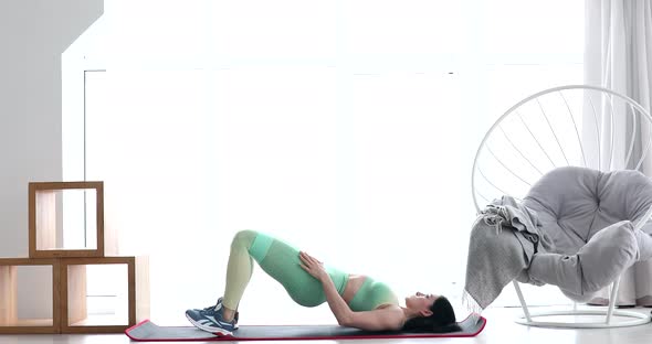 Brunette woman making fitness exercises on mat.